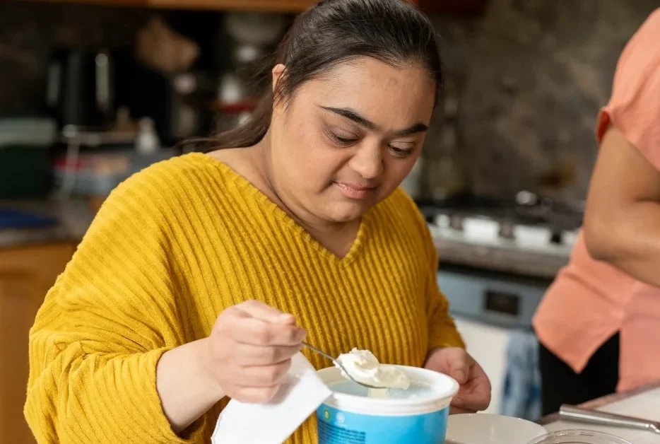 Disabled Indian girl scooping out yoghurt at home