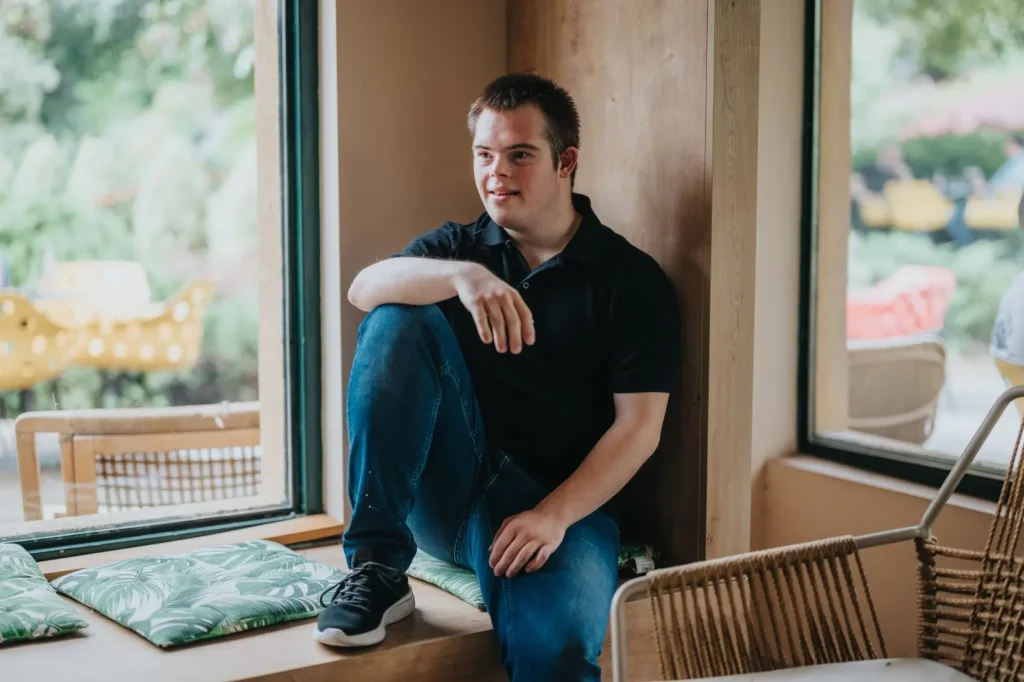Disabled man with down syndrome sitting on bench smiling